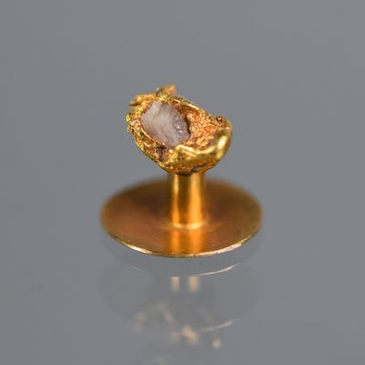 une bague en or sertie d'une pierre, posée sur un socle
