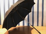 a black umbrella sitting on a wooden table with a blue and white striped wall behind it