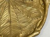 a gold plate with a leaf on it on a table