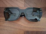 des lunettes de soleil noires posées sur une table en bois, à côté d'une paire de lunettes noires