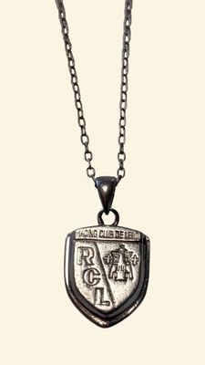 a close up of a silver necklace with a shield on it
