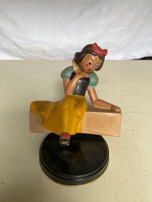 une petite figurine représentant une femme assise sur un banc