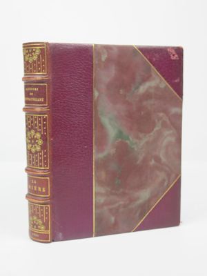 un vieux livre à la couverture rouge posé sur une surface blanche