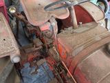 several old tractors are parked in a row in a garage