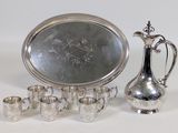 a silver plate with a silver pitcher and cups on it
