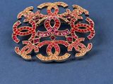 a close up of a red and gold broochle on a blue surface