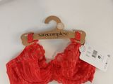red lace bralette on a hanger with a price tag