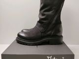 Des bottes en cuir noir avec des fermetures éclair sont posées sur une boîte