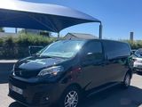 une camionnette noire garée sur un parking, à l'abri d'un parasol
