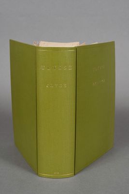 two green books sitting on top of each other on a gray surface