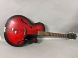 une image représentant une guitare rouge et noire posée sur une surface blanche
