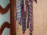 many ties hanging on a wooden rack in a room