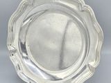 a silver plate with a scalloped edge on a gray background