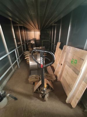 Plusieurs palettes de bois sont empilées dans un local de stockage