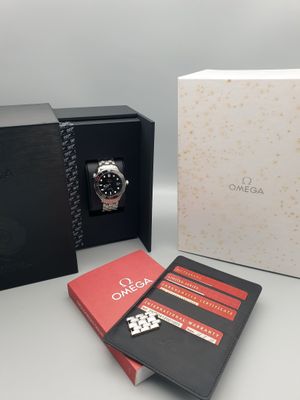 une boîte ouverte contenant une montre, avec un carnet à côté