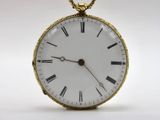 a gold pocket watch with roman numerals on the face