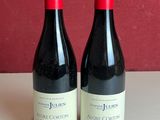 two bottles of red wine sitting on a table