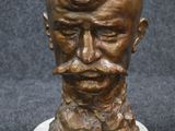 bronze bust of a man with a mustache and moustache on a marble base