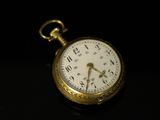a gold pocket watch sitting on a black surface