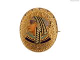 une image montrant un gros plan d'une broche en or représentant le visage d'une femme