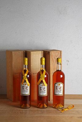three bottles of liquor sit in front of a wooden box on a table