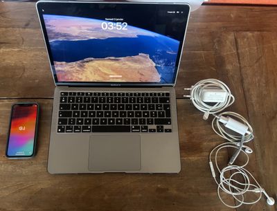 a laptop computer sitting on top of a wooden table next to a cell phone