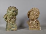 deux petits bustes en bronze représentant un homme et une femme, posés sur une table