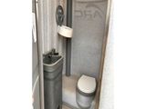 a bathroom with a toilet and a trash can in it