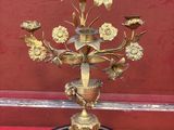 un vase doré avec des fleurs sur une base noire