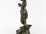 a bronze statue of a woman holding a bird on a rock