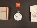 une montre de poche, un livre et un sac posés sur une table