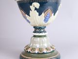 a blue vase with a green base on a white table