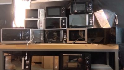 de nombreux micro-ondes et grille-pain posés sur une étagère dans une pièce