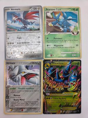 quatre cartes Pokémon différentes sont posées sur une surface blanche