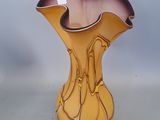 a yellow vase sitting on a table with a white wall in the background