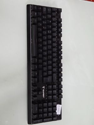 un clavier noir accroché à un mur blanc, sur lequel est collé un autocollant