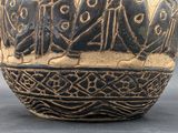 a black and gold vase that has a picture of a group of people on it