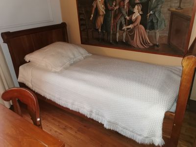 a bed that is in a room with a painting on the wall