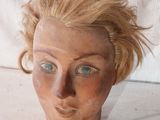 une tête de femme en argile, avec un collier autour du cou