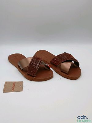 Les sandales marron sont posées sur une surface blanche, avec une étiquette de prix