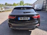the rear end of a black car parked in a parking lot