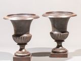 deux vases en argent posés sur un socle en bois