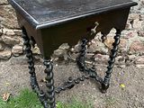 une petite table avec un tiroir, placée devant un mur en pierre