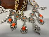 an image of a necklace with orange beads and pearls on a table