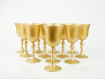 six coupes en or sont alignées sur une surface blanche