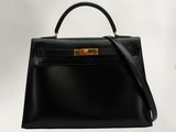 a black leather handbag with gold hardware on a white background