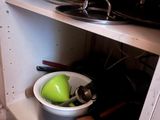 a bowl with a green apple in it on a shelf