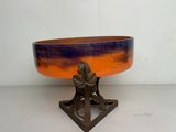 un bol orange et bleu posé sur un socle en métal