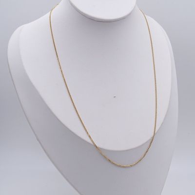 a white mannequin with a gold chain on it