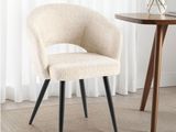 a white chair with black legs and a table with a vase of flowers on it